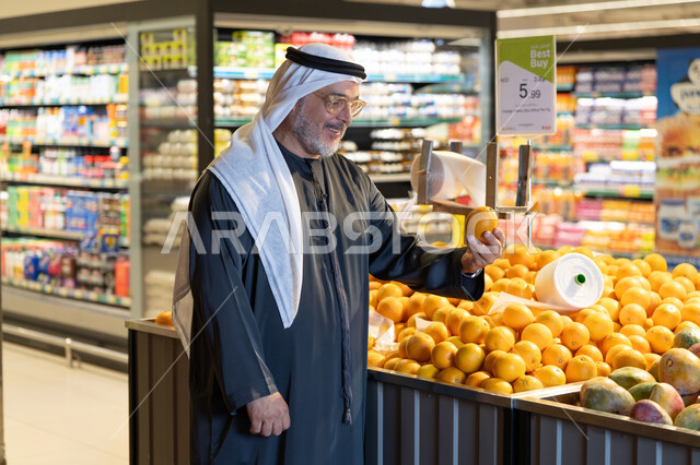 رجل إماراتي يتسوق البرتقال الطازج في السوبر ماركت