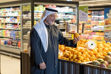 رجل إماراتي يتسوق البرتقال الطازج في السوبر ماركت