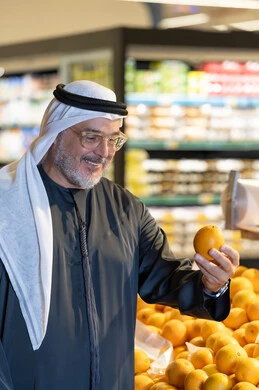 رجل إماراتي يتسوق الفواكه الطازجة في السوبر ماركت
