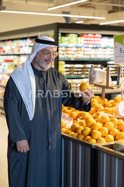رجل إماراتي يتسوق لشراء البرتقال الطازج من السوبر ماركت