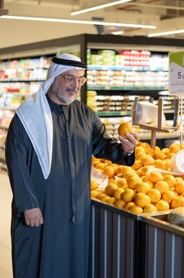 رجل إماراتي يتسوق لشراء البرتقال الطازج من السوبر ماركت