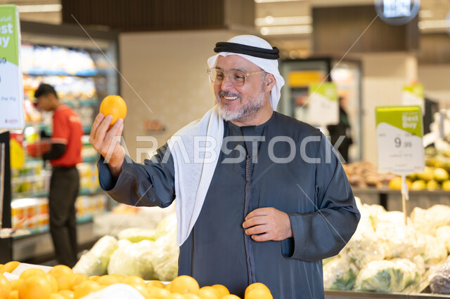 رجل إماراتي يتسوق الفواكه الطازجة في السوبر ماركت