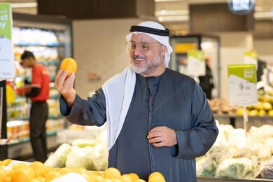 رجل إماراتي يتسوق الفواكه الطازجة في السوبر ماركت