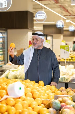 رجل إماراتي يتسوق البرتقال الطازج في السوبر ماركت