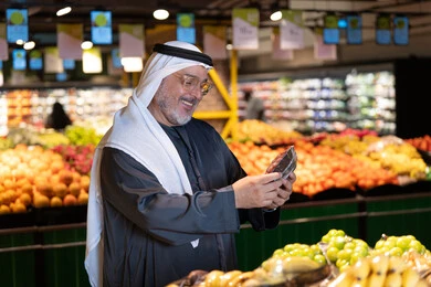 رجل إماراتي يتسوق في قسم الخضار بالسوبر ماركت