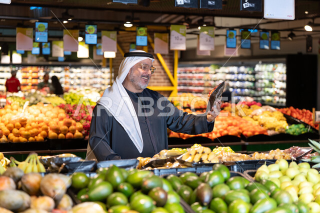 رجل إماراتي يتسوق الخضروات والفواكه في السوبر ماركت