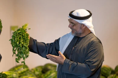 رجل إماراتي يمسك بقدونس طازج في متجر بقالة