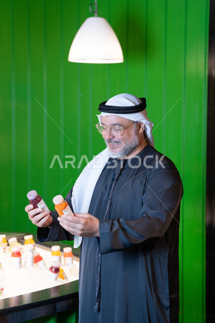 رجل إماراتي بالثوب يتفحص زجاجات العصير الطازج