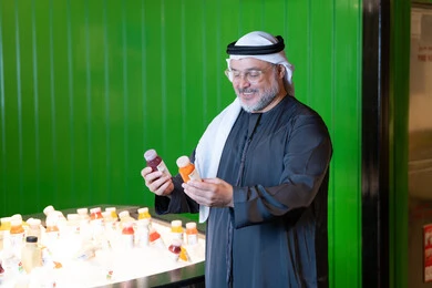 رجل إماراتي يمسك زجاجات عصير في السوبر ماركت