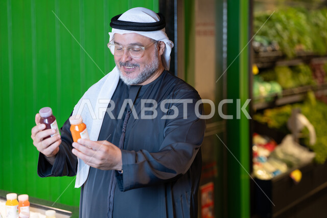 رجل خليجي يختار عصير طازج في السوبر ماركت