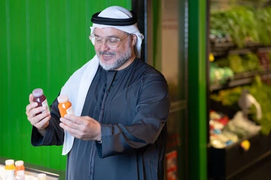 رجل خليجي يختار عصير طازج في السوبر ماركت