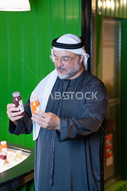Emirati Man Selecting Fresh Juice Bottles in a Shop