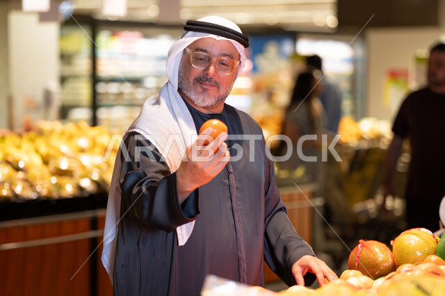 رجل عربي مسن يتسوق الفاكهة الطازجة في السوبر ماركت