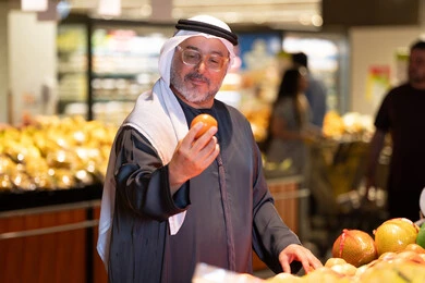 رجل عربي مسن يتسوق الفاكهة الطازجة في السوبر ماركت