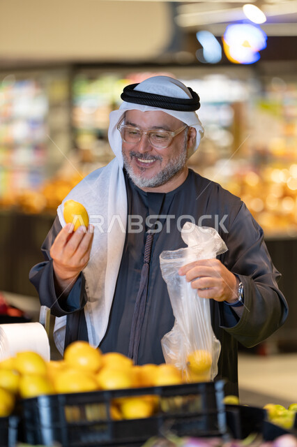 رجل إماراتي يتسوق الليمون الطازج في السوبر ماركت