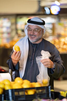 رجل إماراتي يتسوق الليمون الطازج في السوبر ماركت