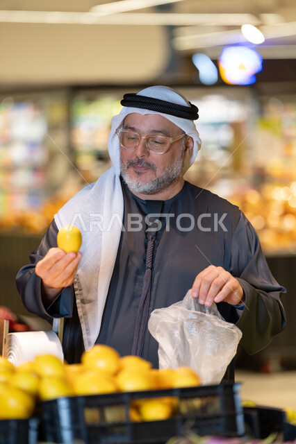 رجل إماراتي يتسوق الليمون الطازج في السوبر ماركت