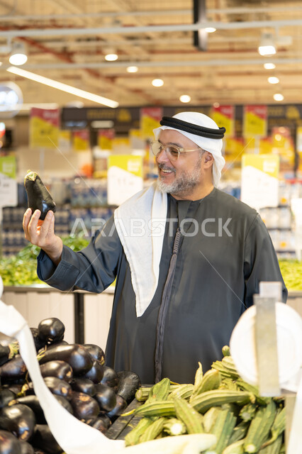 رجل إماراتي يتسوق الخضروات الطازجة في السوبر ماركت