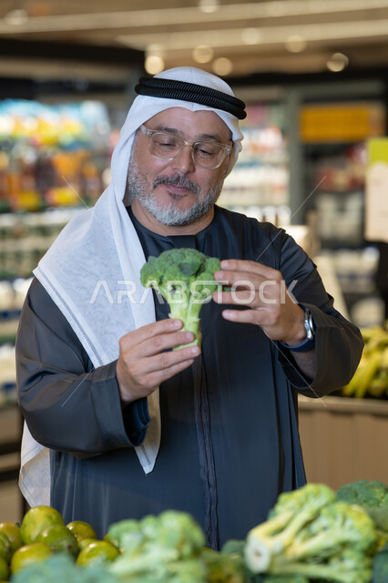 رجل إماراتي يتسوق الخضروات الطازجة في السوبر ماركت