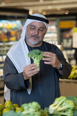 رجل إماراتي يتسوق الخضروات الطازجة في السوبر ماركت