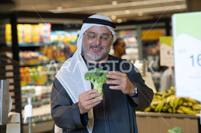 رجل إماراتي يتسوق الخضروات الطازجة في السوبر ماركت