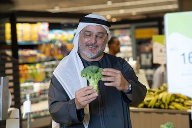 رجل إماراتي يتسوق الخضروات الطازجة في السوبر ماركت