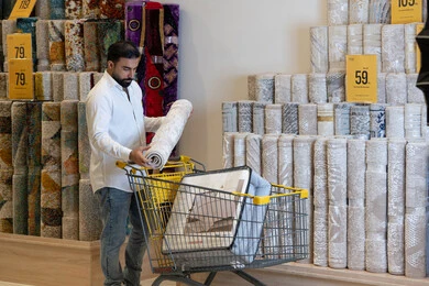 رجل عربي يتسوق لشراء السجاد في متجر مفروشات منزلية