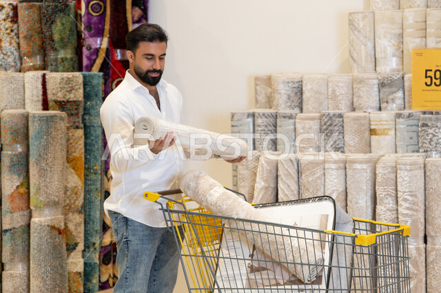 رجل عربي يتسوق لشراء السجاد في متجر ديكور منزلي