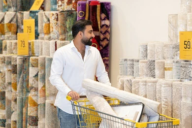 رجل عربي يتسوق للسجاد في متجر ديكور منزلي رجل عربي يتسوق للسجاد في متجر ديكور منزلي