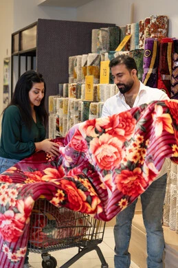 زوجان عربيان يتسوقان لشراء بطانية وردية في المتجر