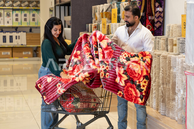 زوجان عربيان يتسوقان لشراء مفروشات وبطانية من متجر