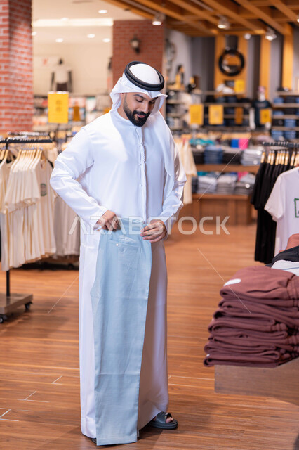 رجل سعودي يتسوق الملابس في متجر تجاري