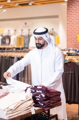 رجل عربي يتسوق الملابس في متجر تجاري