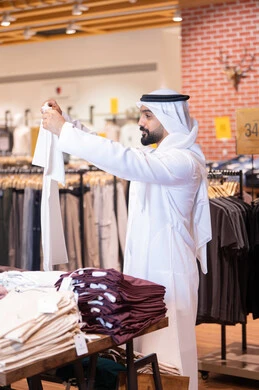 رجل إماراتي يتسوق في متجر ملابس حديث