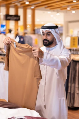 رجل عربي يتسوق لشراء الملابس في متجر حديث