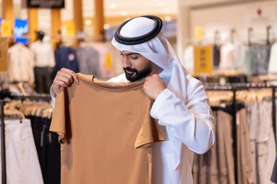 رجل إماراتي يتسوق الملابس في متجر تجزئة