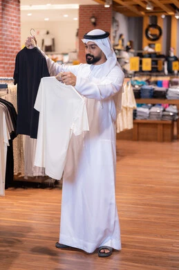 رجل إماراتي يتسوق لشراء ملابس في متجر تجزئة