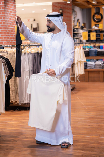 رجل إماراتي يتسوق لشراء الملابس في متجر حديث