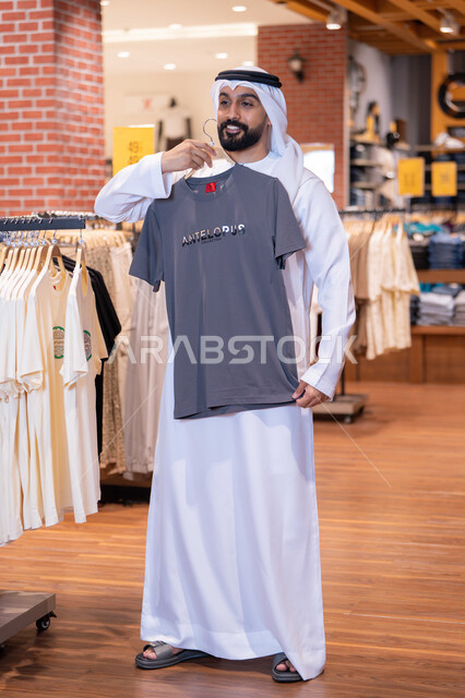 رجل إماراتي يتسوق لشراء الملابس داخل متجر تجاري