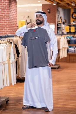 رجل إماراتي يتسوق لشراء الملابس داخل متجر تجاري