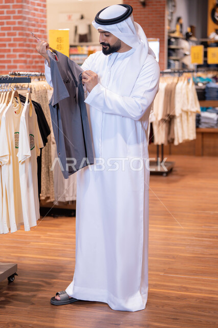 رجل إماراتي يتسوق لشراء الملابس في متجر تجزئة