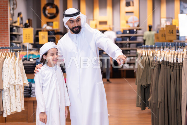 أب وابنه بزي إماراتي يتسوقان في متجر ملابس