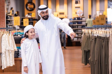 أب وابنه بزي إماراتي يتسوقان في متجر ملابس أب وابنه بزي إماراتي يتسوقان في متجر ملابس