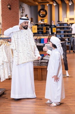 Emirati Man and Boy Shopping in Traditional Clothing Store