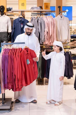رجل إماراتي وابنه يتسوقان الملابس في المتجر