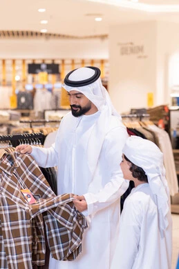 رجل إماراتي وابنه يتسوقان في متجر ملابس