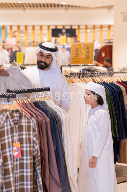 أب وابنه بزي إماراتي يتسوقان في متجر ملابس