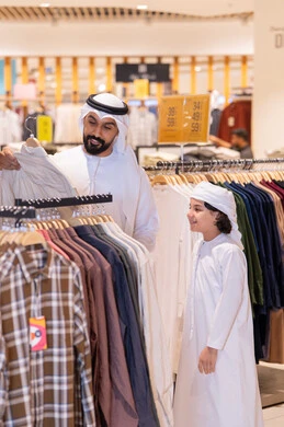 أب وابنه بزي إماراتي يتسوقان في متجر ملابس أب وابنه بزي إماراتي يتسوقان في متجر ملابس