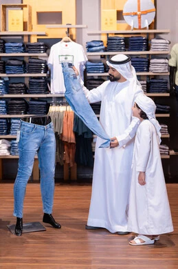 رجل إماراتي وطفل يتسوقان في متجر ملابس