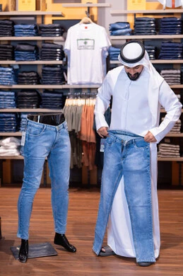 رجل سعودي يتسوق لشراء بنطال جينز في متجر ملابس رجل سعودي يتسوق لشراء بنطال جينز في متجر ملابس